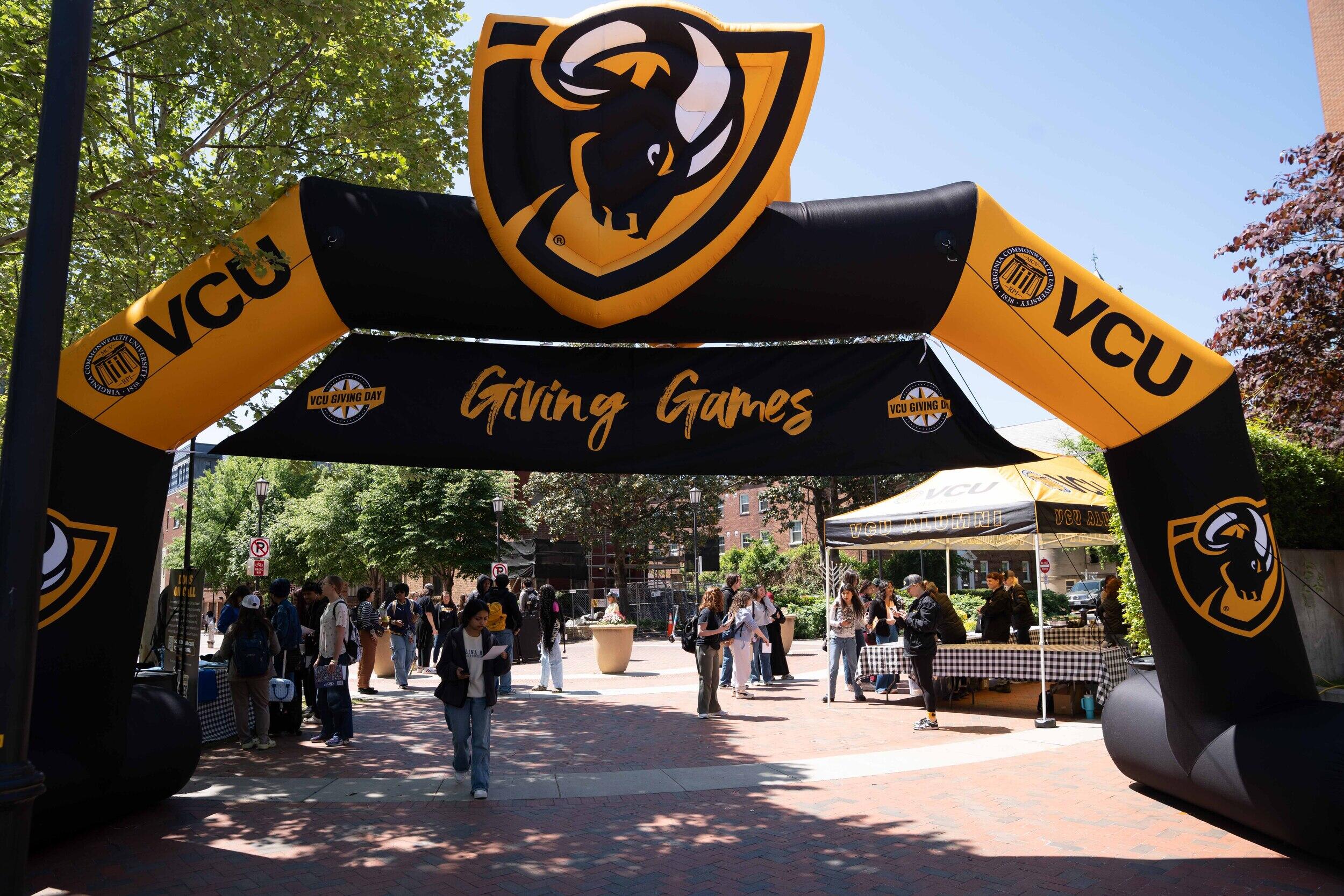 A photo of a black and yellow inflatable arch with people walking under it. 