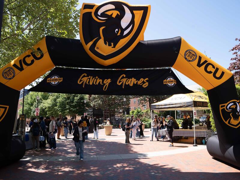 A photo of a black and yellow inflatable arch with people walking under it. 
