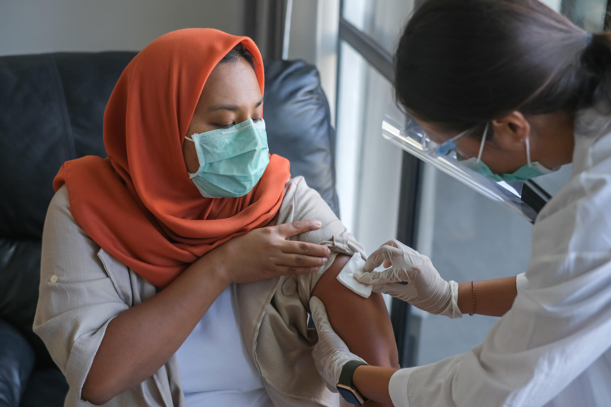 A photo of a doctor pressing a pad on a woman's arm. 