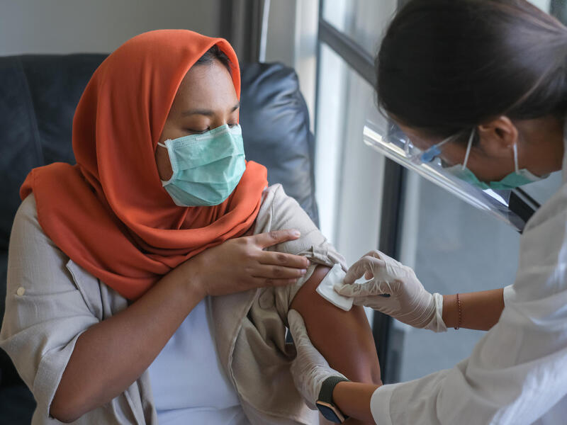 A photo of a doctor pressing a pad on a woman's arm. 