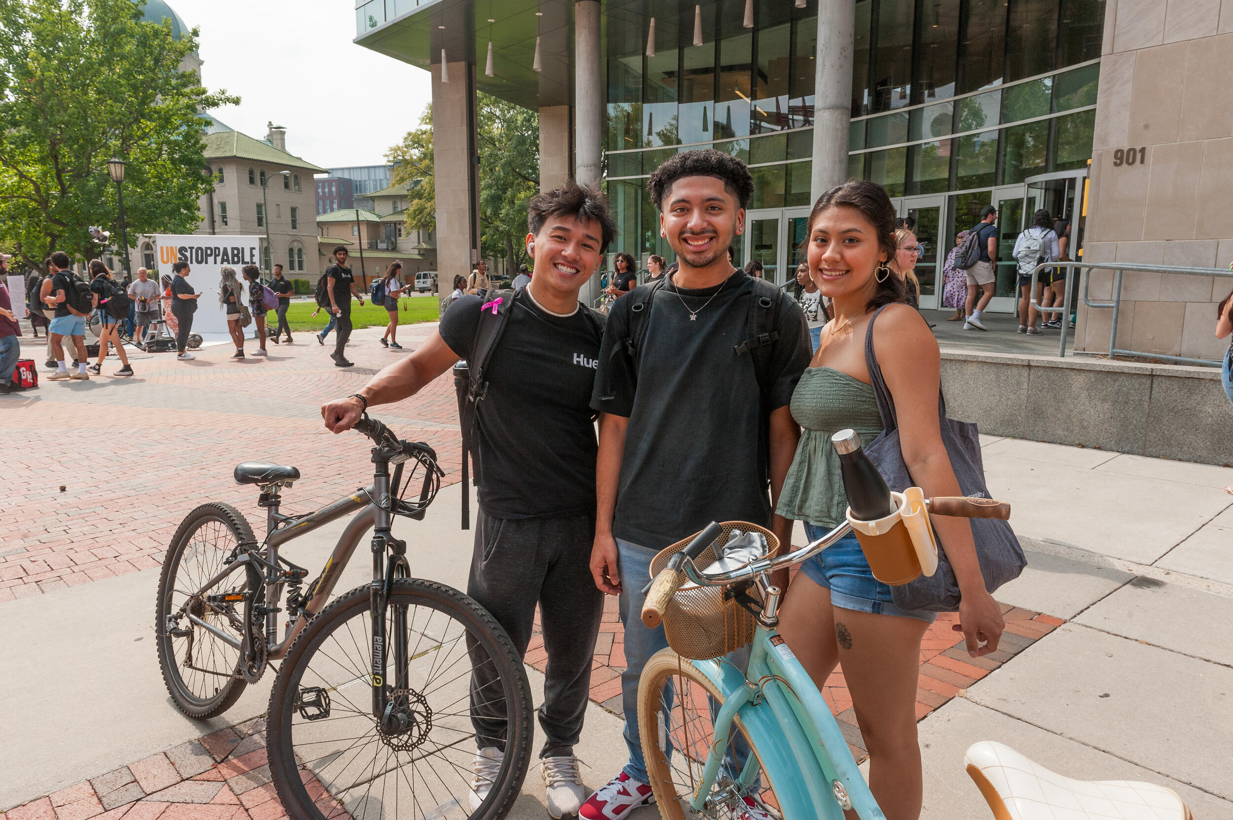 Three people standing and smiling in front of a library 