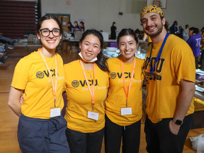 A group photo of four people standing next to each other in a row. 