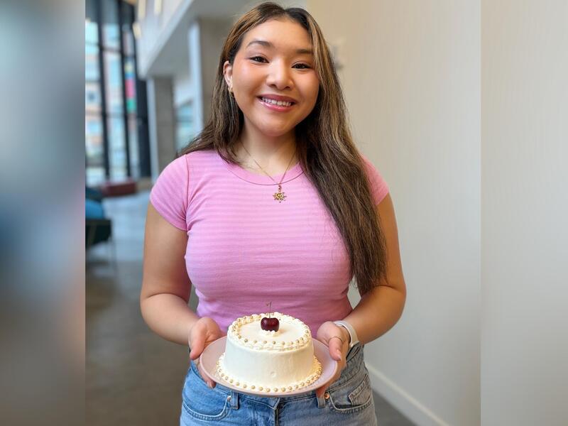 A photo of a woman holing a cake and smiling 