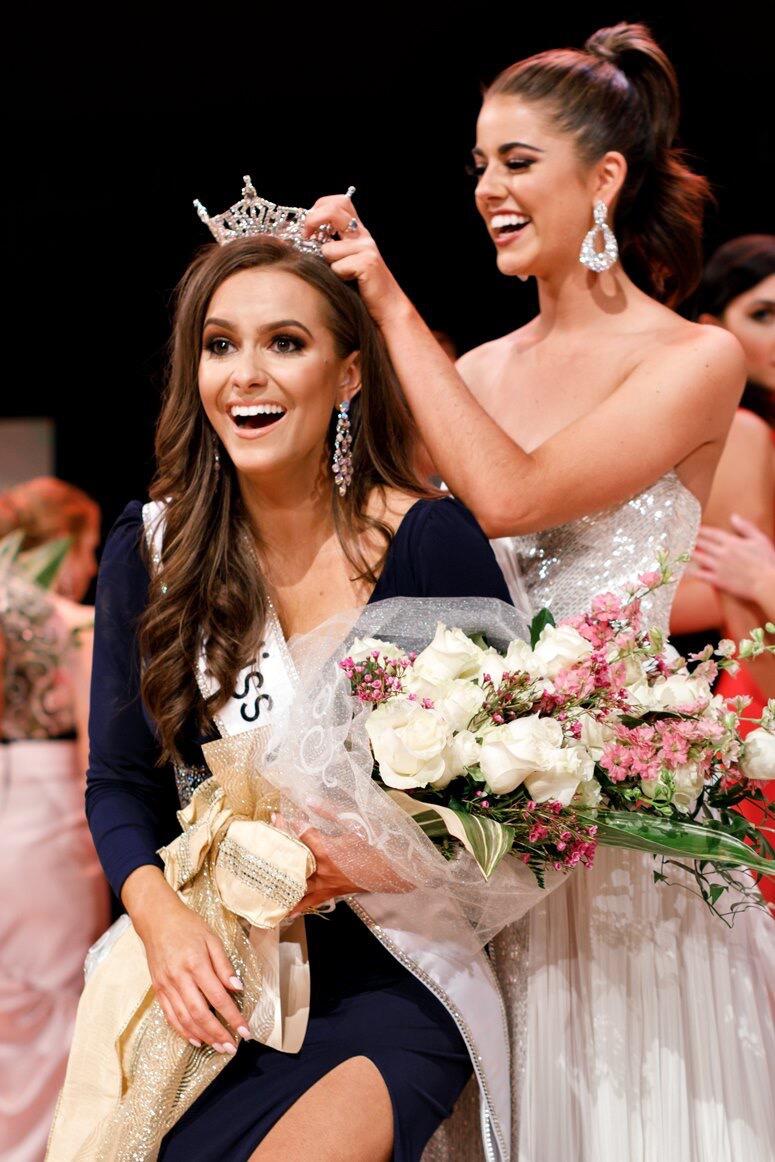 A woman is placing a crown on the head of Camille Schrier in honor of winning the Miss Virginia competition.