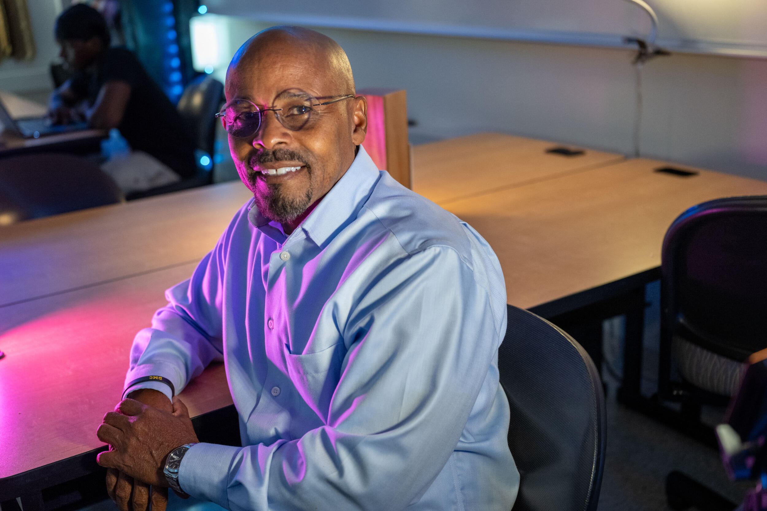 A man sits and leans on a conference table.
