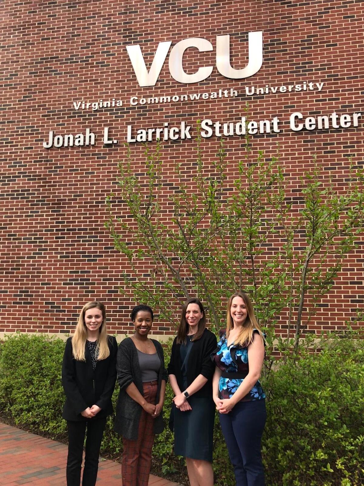 Four people stand in front of VCU building. 
