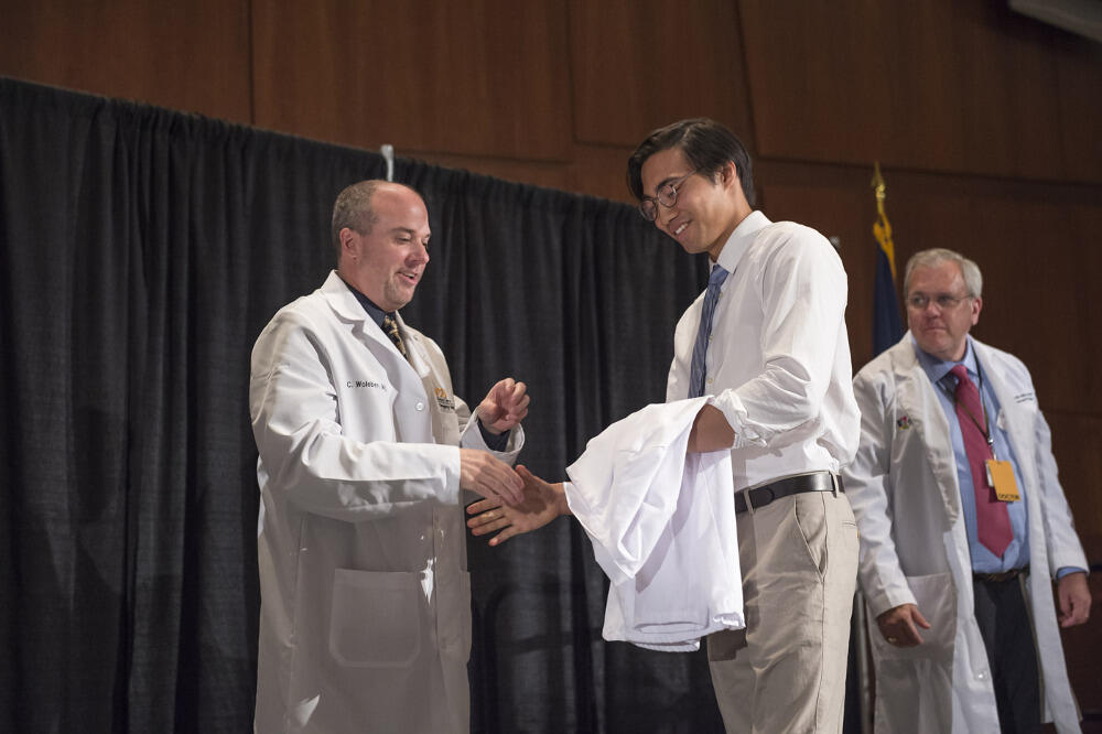 Christopher Le receives his white coat from Christopher Woleben, M.D., associate dean for student affairs, at the School of Medicine White Coat Ceremony on July 30, 2015. <br>Photo by Allen Jones, VCU University Marketing.