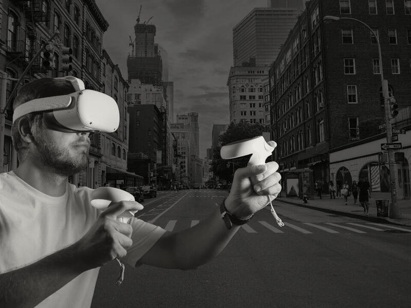 A photo of a man wearing a VR headset. The background is a city street. 