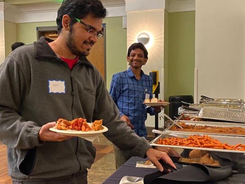 Two men at a buffet table holding plates.