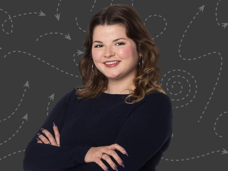 A photo of a woman from the chest up with her arms crossed against her chest. 