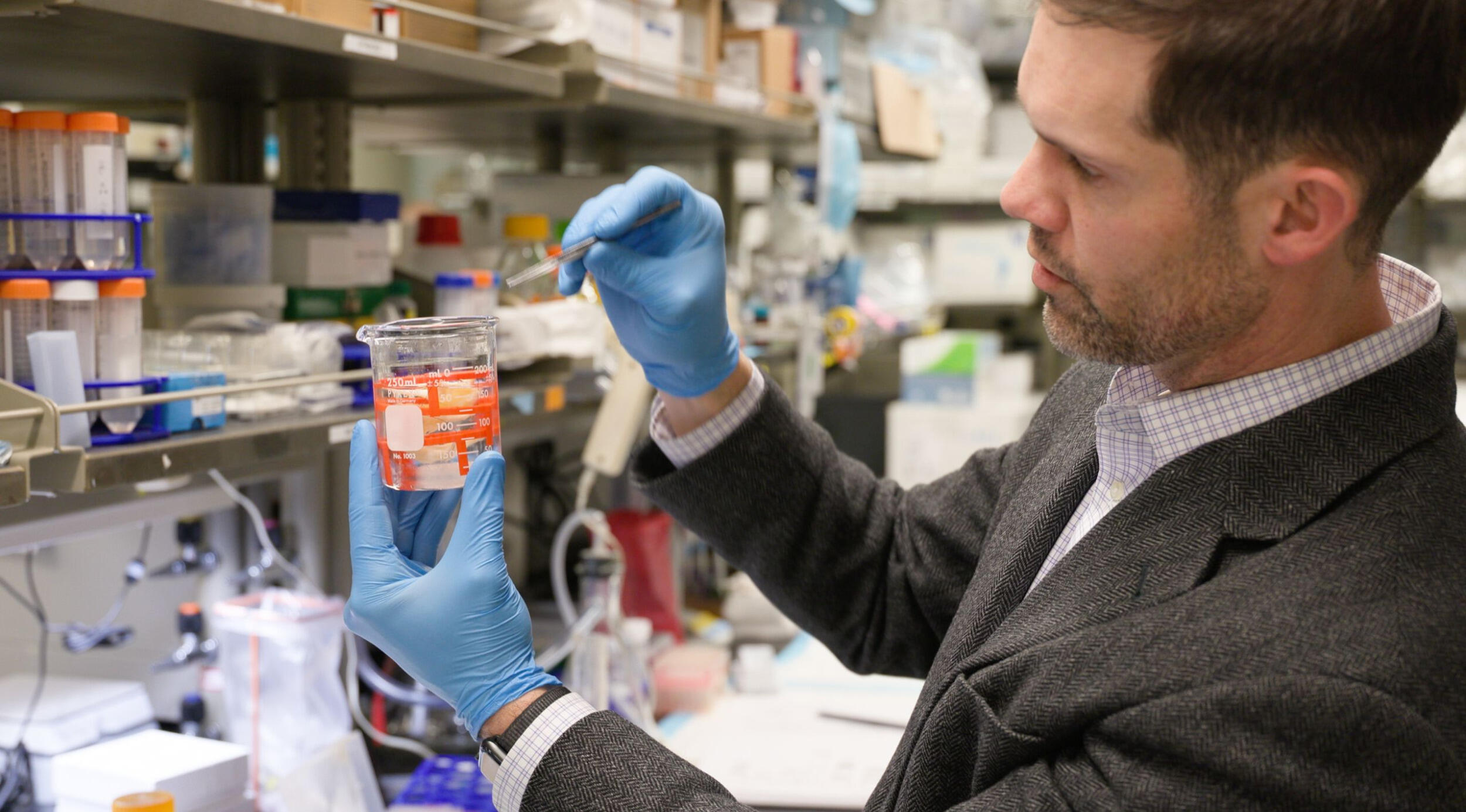 A man in blue safety gloves works in a lab.
