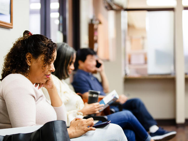 A photo of three people sitting in a waiting room.