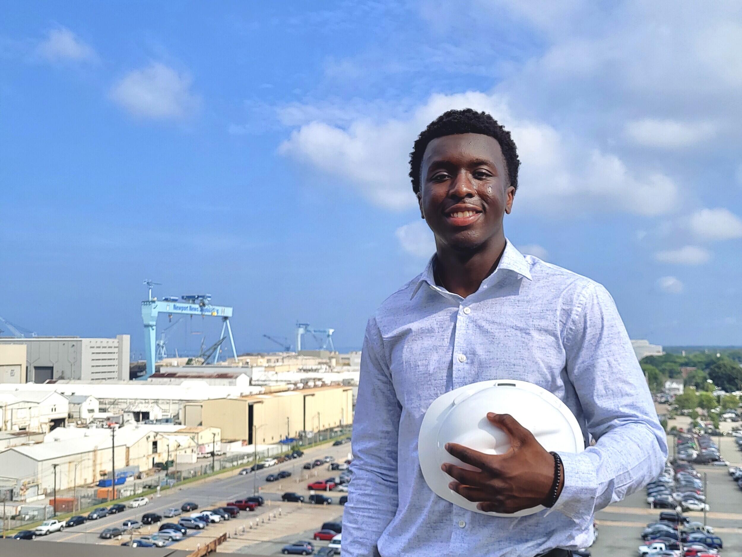 A man standing holding a saftey helment. 