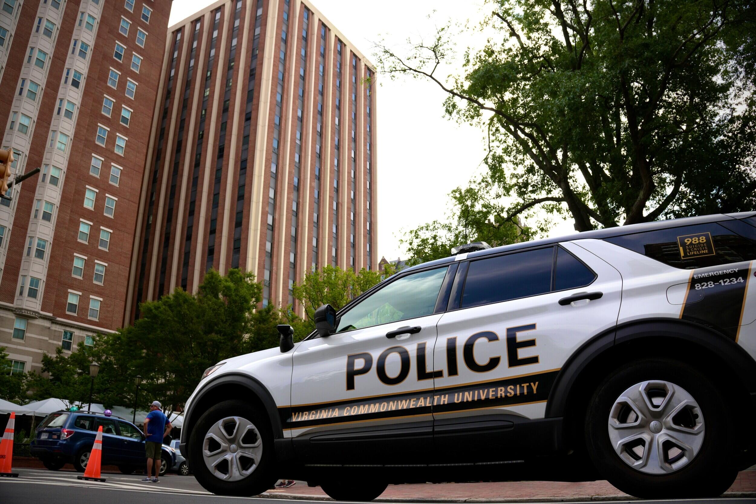 A photo of a police SUV parked across the street from dorm buildings. 