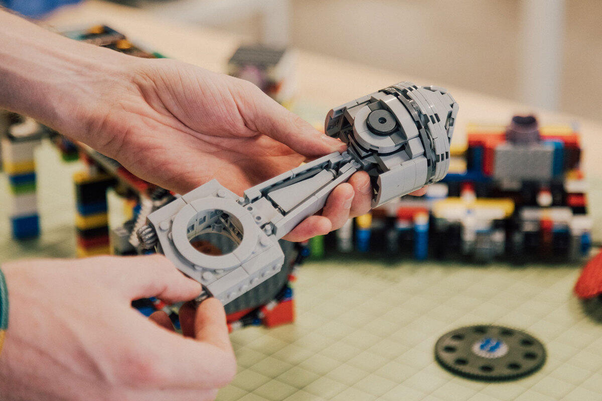 Two hands holding an item made out of gray lego bricks 