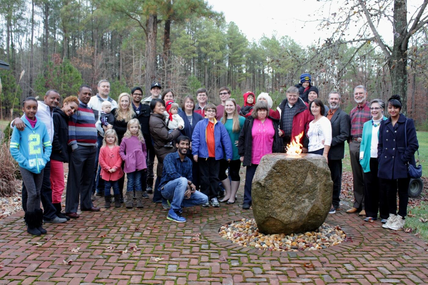 Todd and Jill Vander Pol (fourth and fifth from the right) share their Thanksgiving celebration with VCU international students Mithun Mathew, kneeling in front, and Karthik Hegde, wearing the black jacket (ninth from the left.) The Vander Pols have invited international students and others from the area without families to take part in their annual celebration. Photo provided by Jill Vander Pol. 