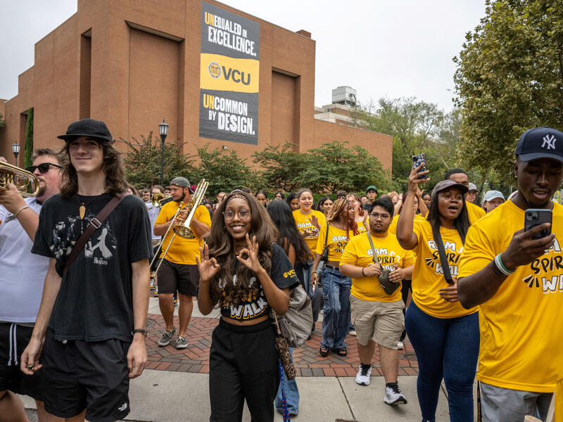 A crowd of men and women walk through a plaza.
