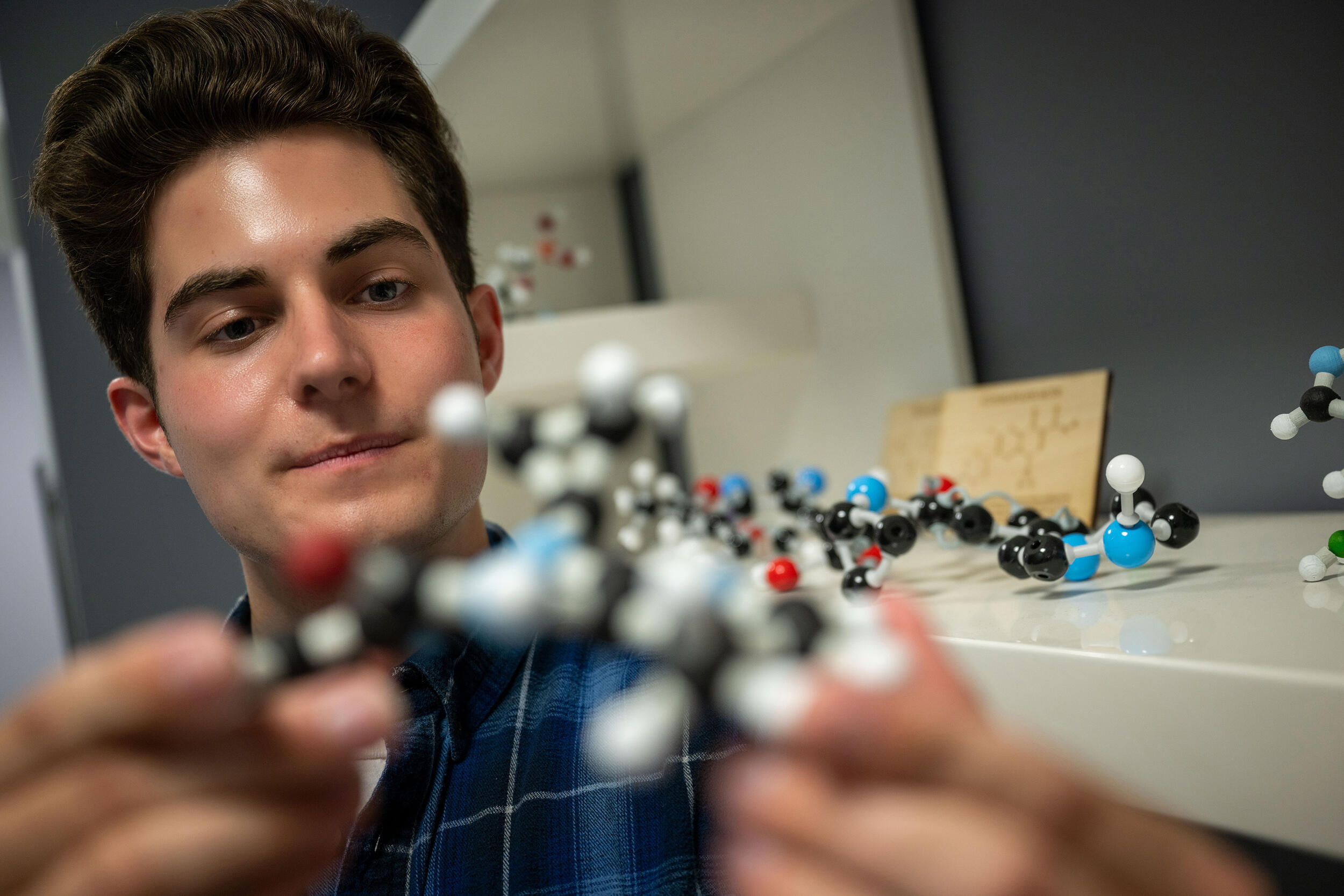 A photo of a man holding a model of a chemical compound. 