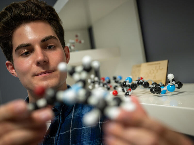 A photo of a man holding a model of a chemical compound. 