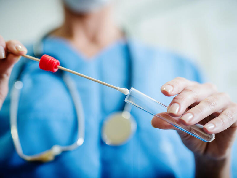 Photo of person in medical scrubs holding a stethoscope.