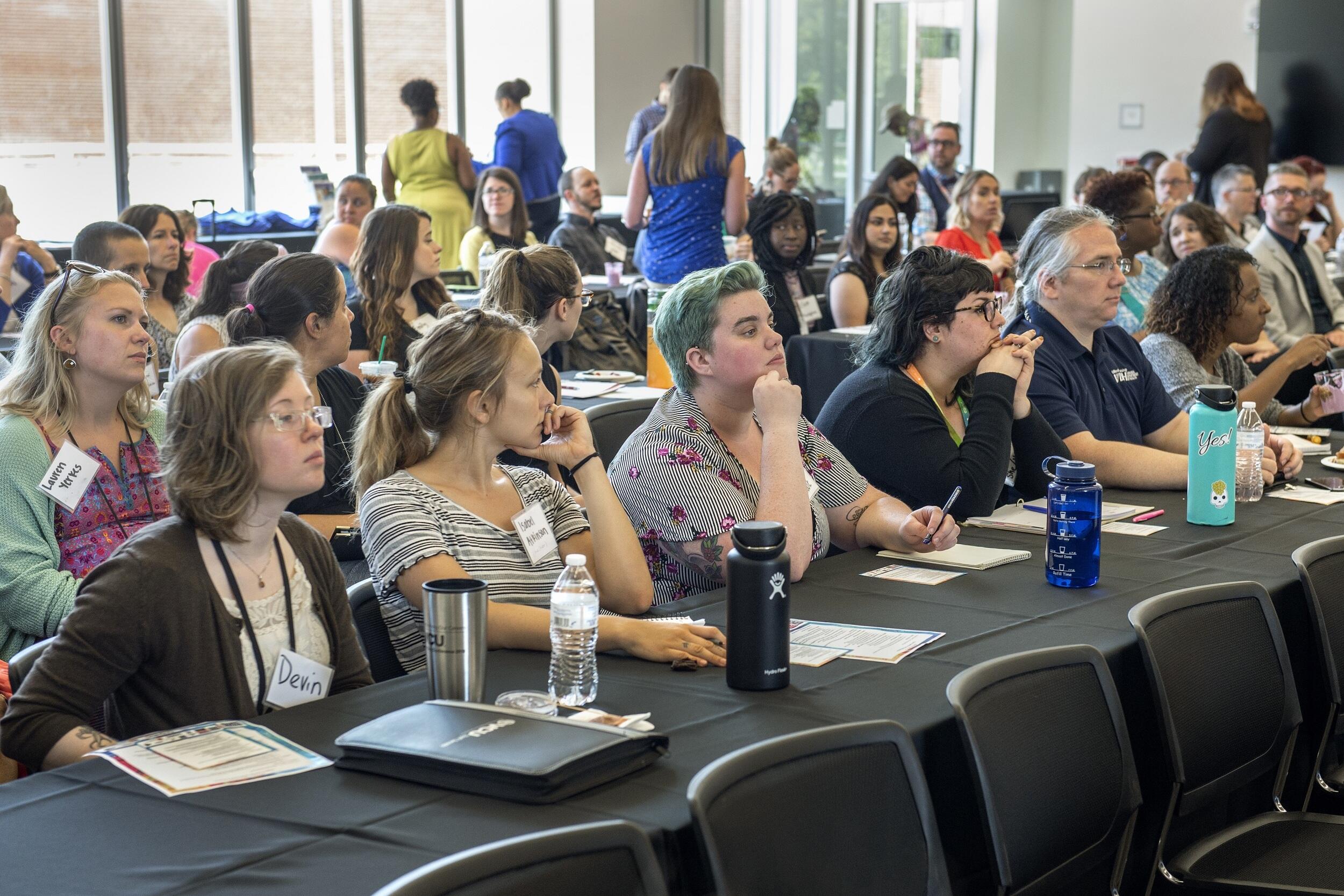 Symposium attendees seated at tables.