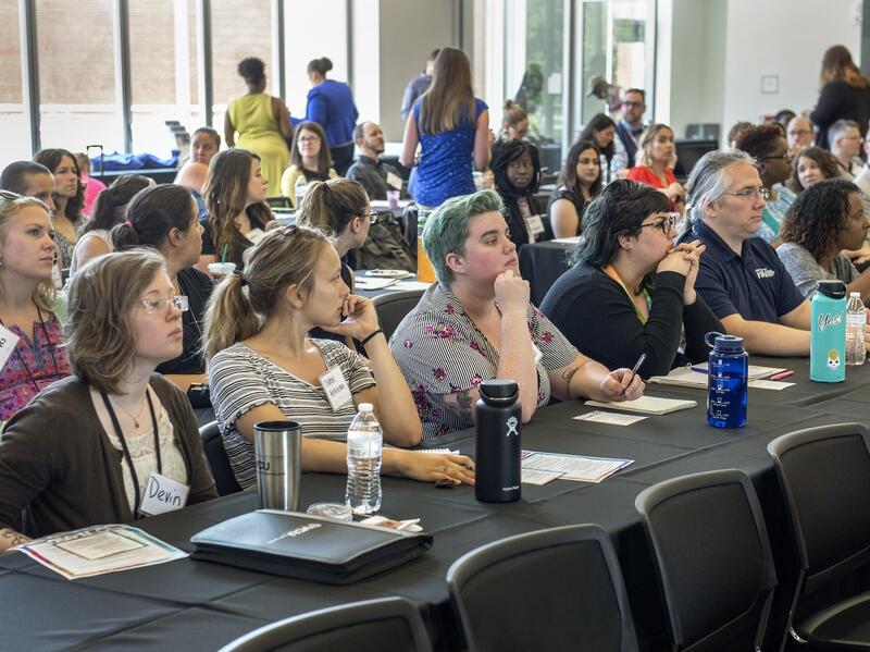 Symposium attendees seated at tables.
