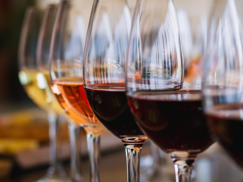 A photo of six glasses of wine lined up next to each other. 