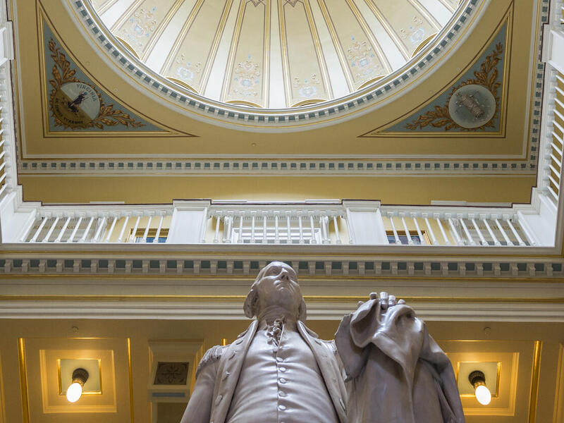 A statue sits underneath the rotunda of a building.