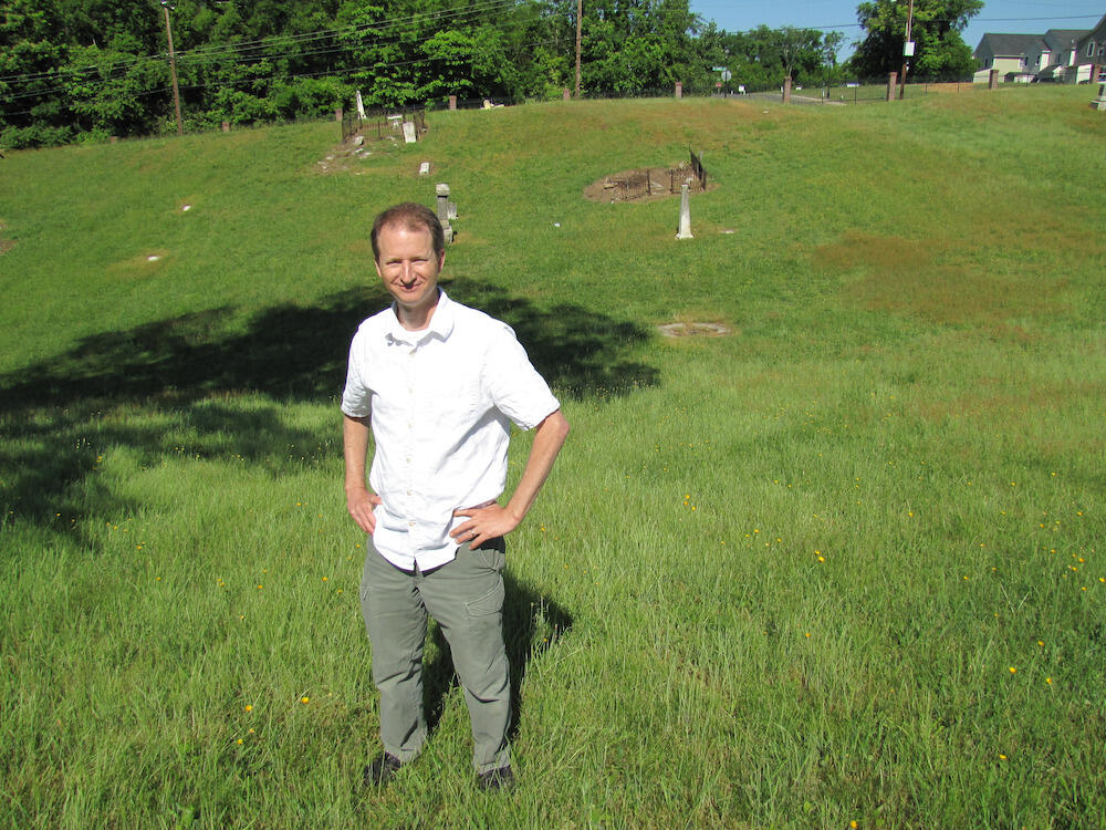 Man stands in cemetery. 