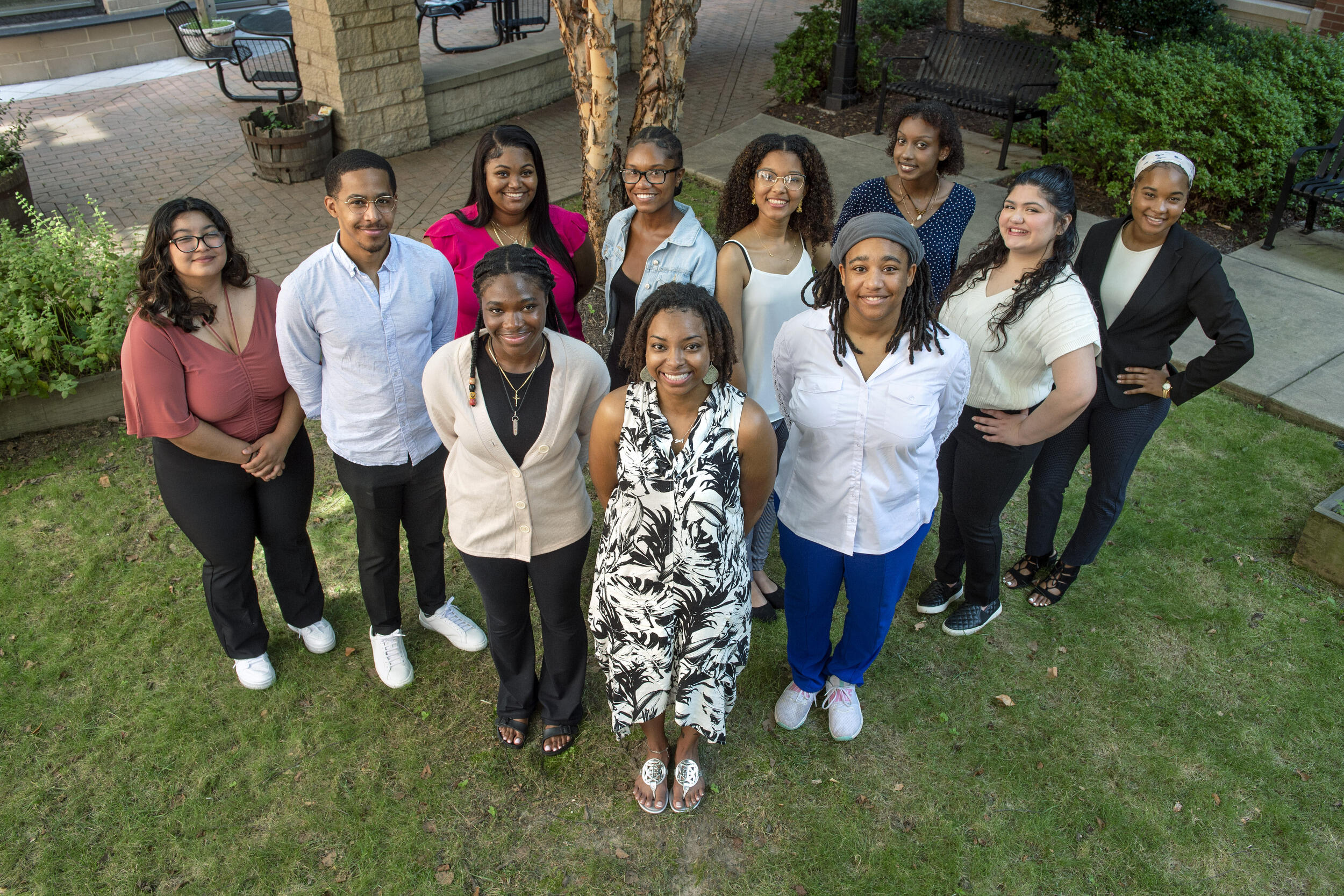 A photo of 11 people standing on grass. 