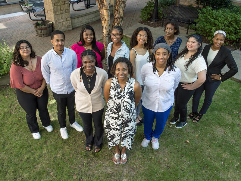 A photo of 11 people standing on grass. 