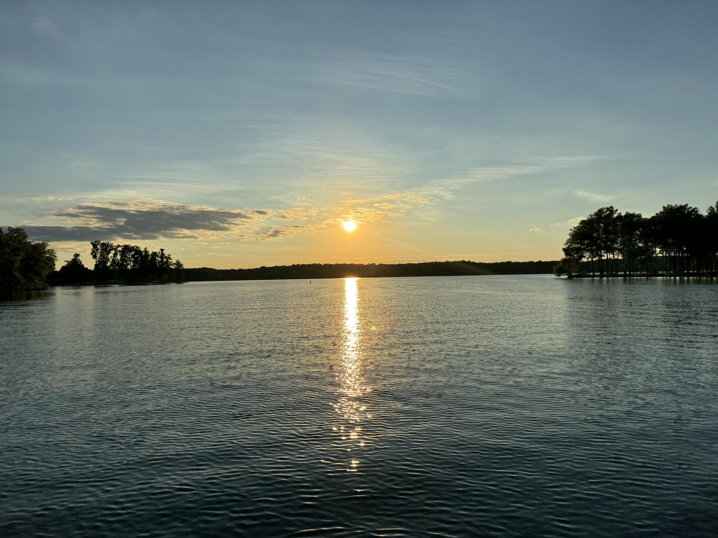 A photo of a lake with the sun reflecting off of the water. 