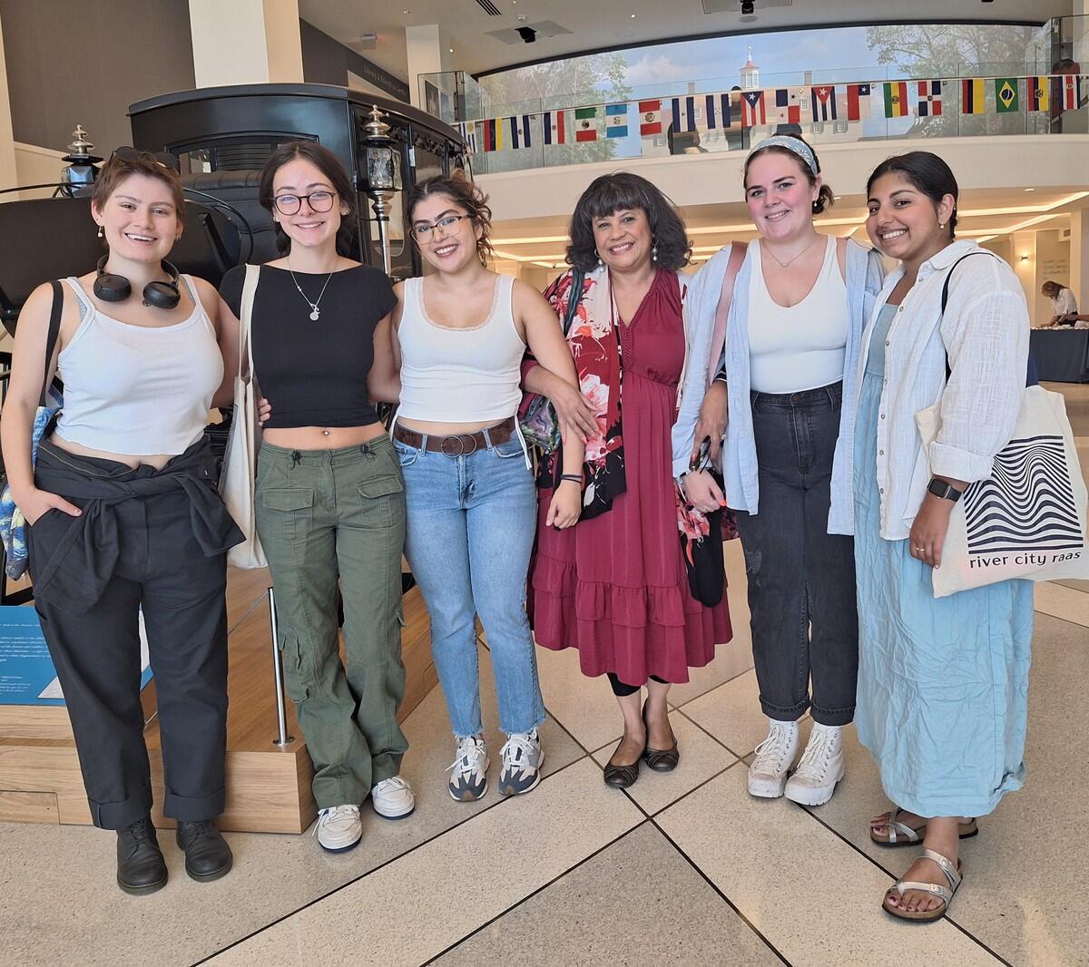 A photo of six women standing next to eachtoher. 