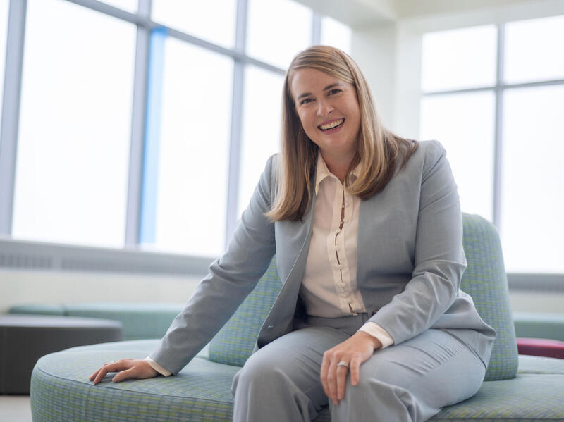 A photo of a woman sitting on a plush circle shaped couch. 