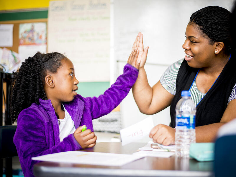 A child high fiving a woman 
