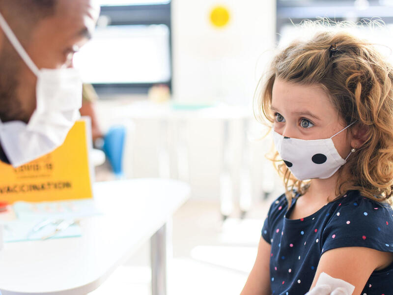 young girl in a mask talking to a doctor