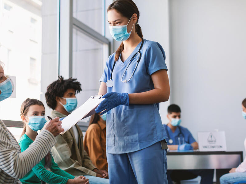 Coronavirus Treatment And Vaccination. Mature Lady In Mask Signing Papers With Doctor In Hospital Waiting-Room. Plasma Donations From Corona Virus Donors, Covid-19 Pandemic Medical Campaign Concept