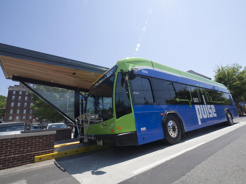 Blue and green bus parked at bus stop.
