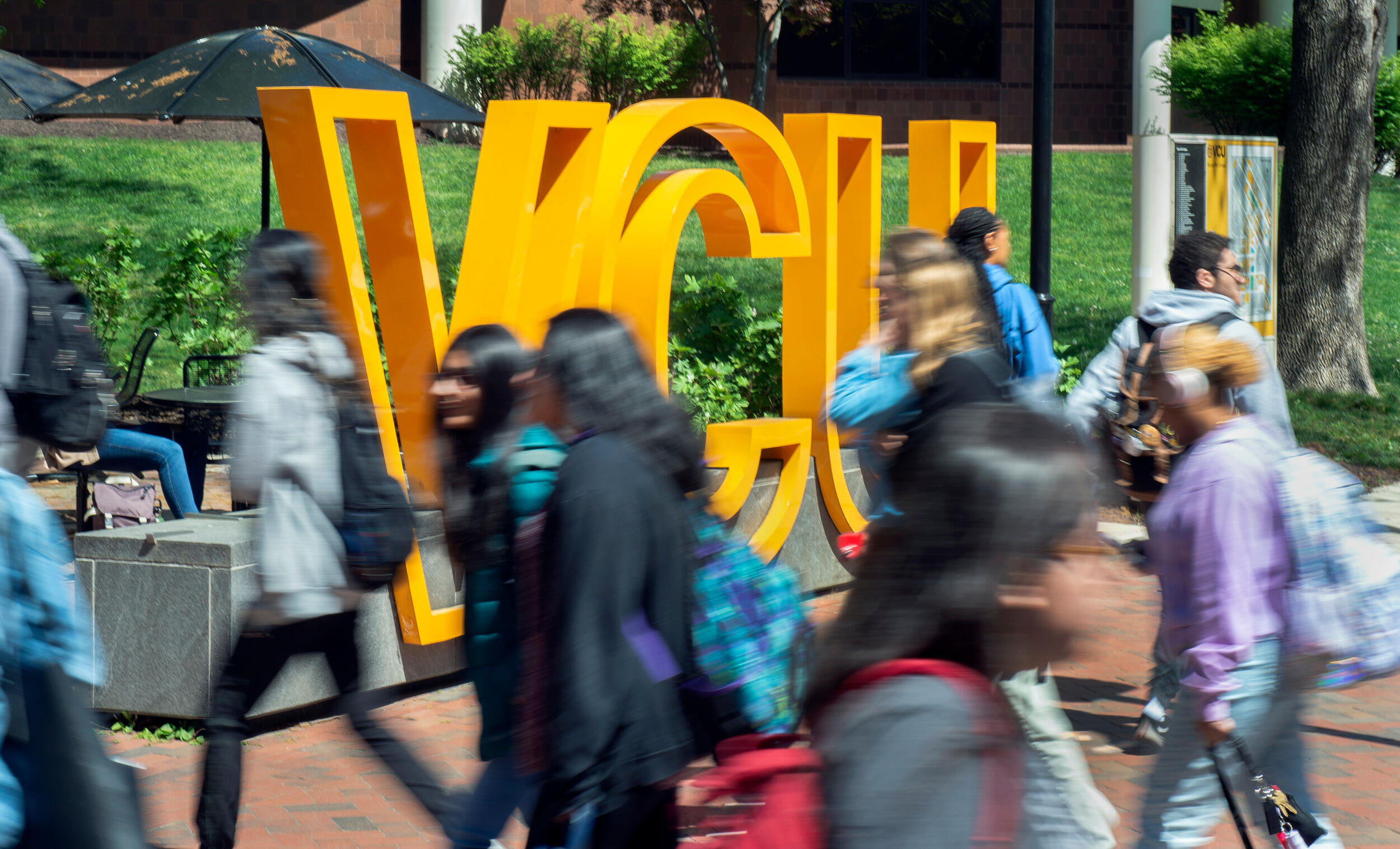 Students walk in front of a yellow VCU sign.