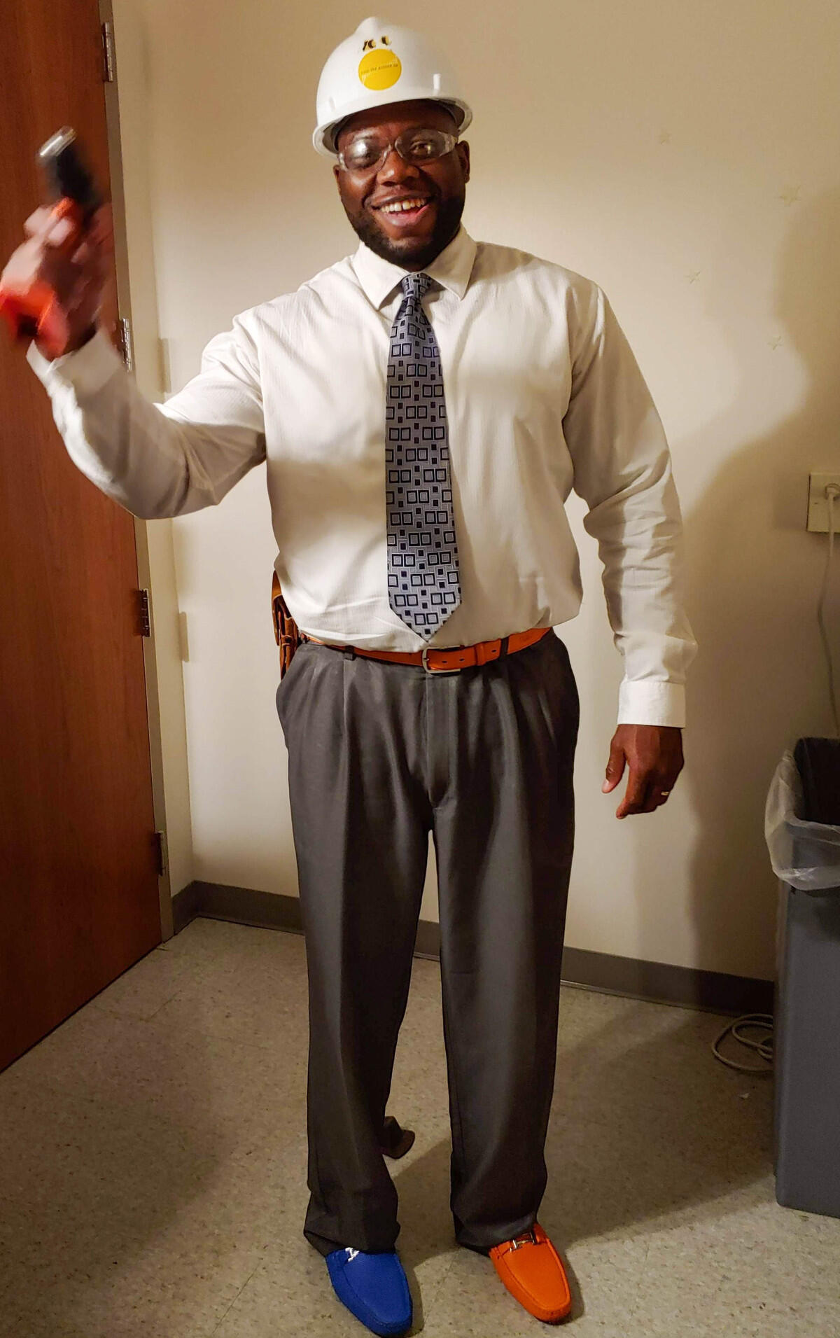 A man smiling wearing a hardhat and safety glasses 