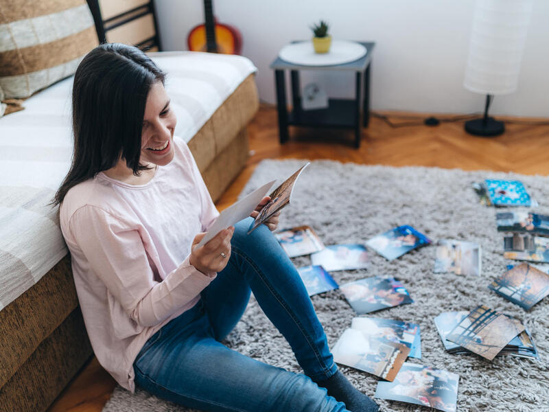 A photo of a woman sitting on the floor, smiling and looking at photos. 