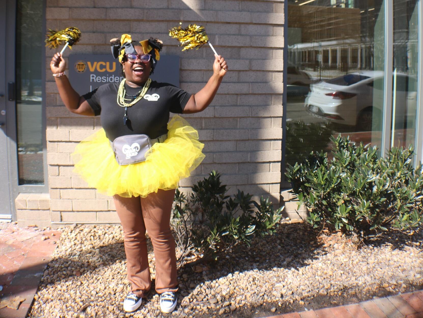 A photo of a woman standing and waving pom poms in the air while smiling