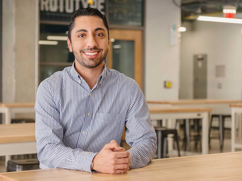A man wearing a button down shirt with his arms on the table 