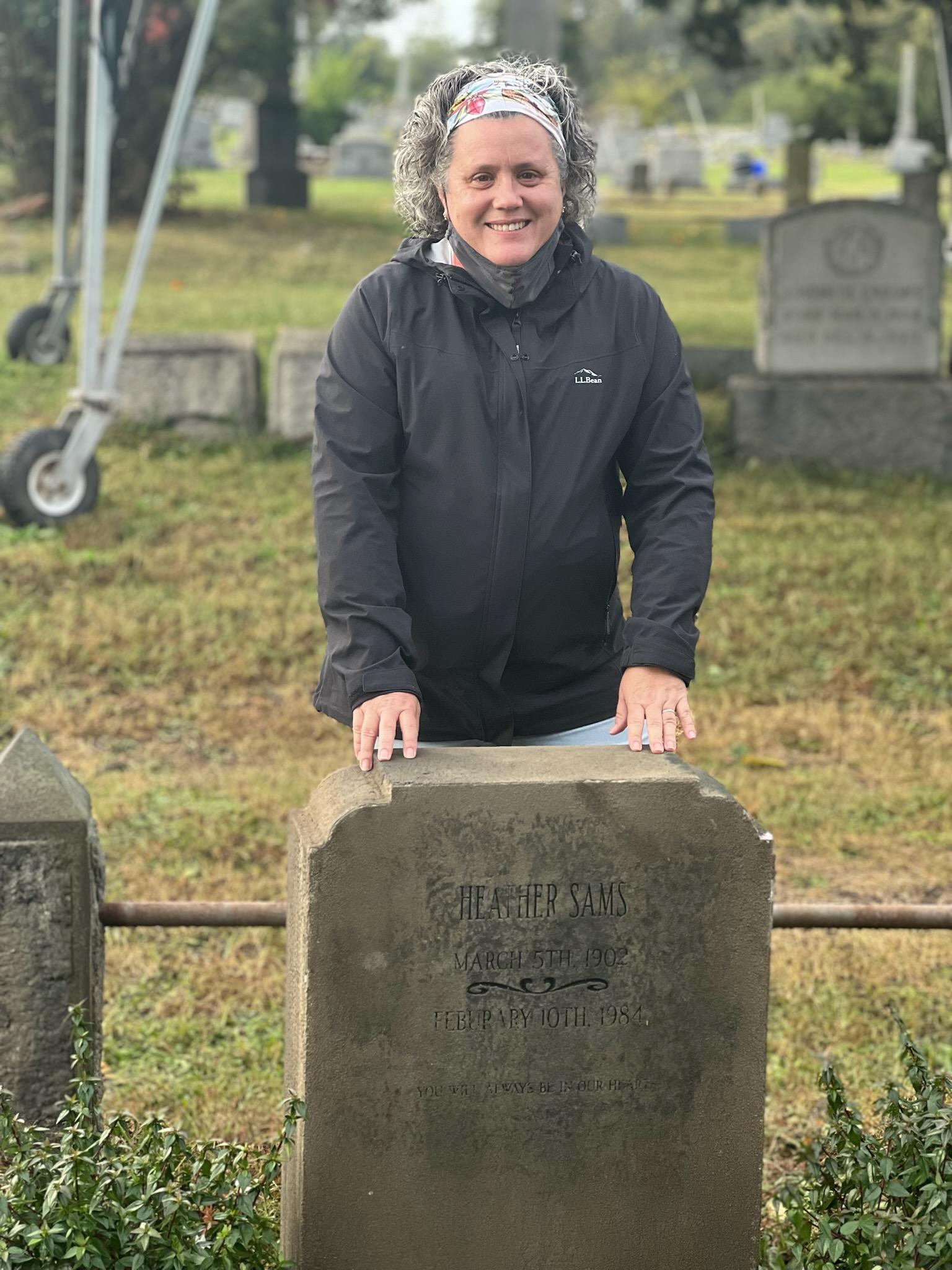 A woman standing behind a tombstone 