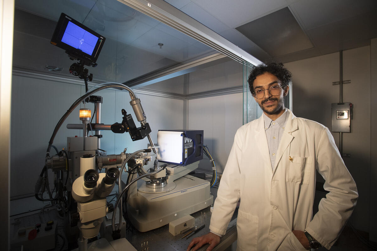 A photo of a man standing next to scientific equipment. 