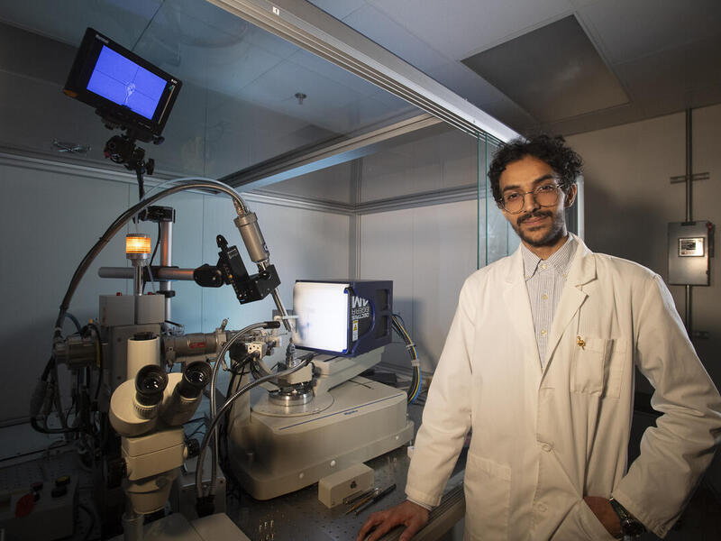 A photo of a man standing next to scientific equipment. 