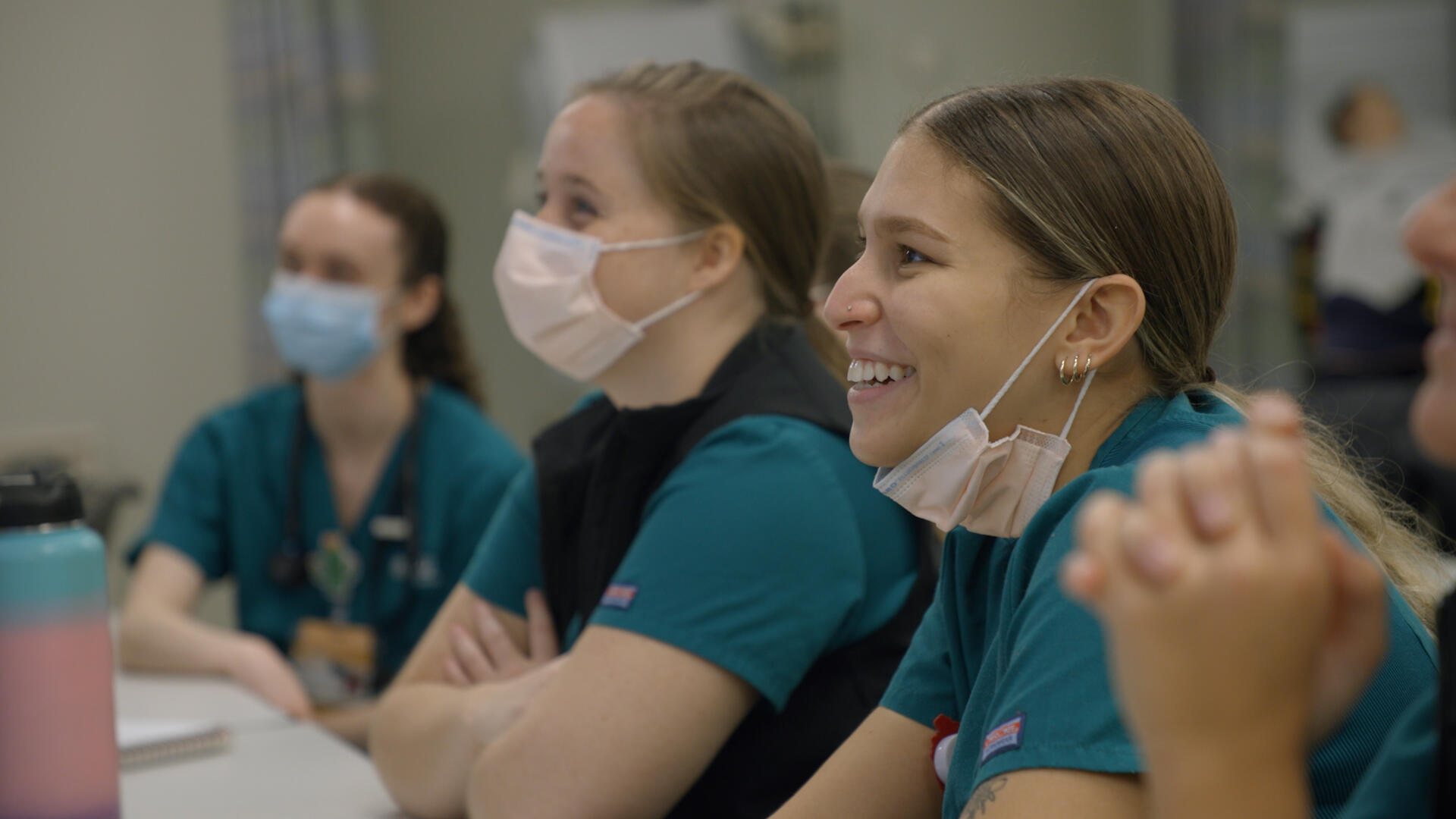 People wearing face masks sitting at a table. 