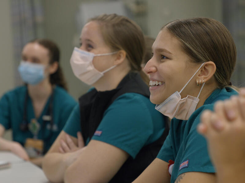 People wearing face masks sitting at a table. 