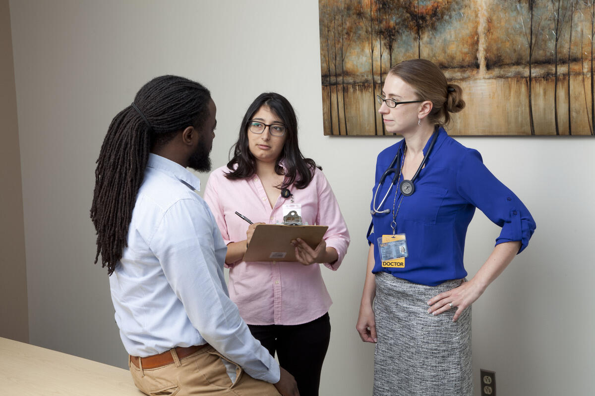 A doctor and another staff person with a clipboard talk with a third person.