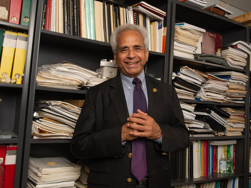 A photo of a man standing in front of a book case. 